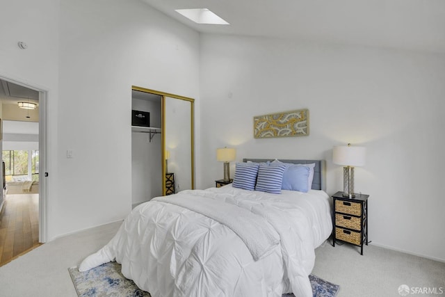 carpeted bedroom with a skylight, a closet, and high vaulted ceiling