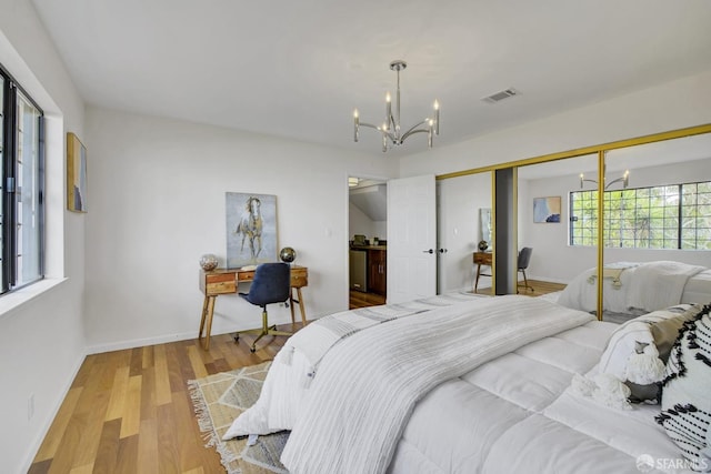 bedroom featuring an inviting chandelier, a closet, and light hardwood / wood-style flooring