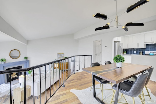 dining room with light hardwood / wood-style flooring and vaulted ceiling