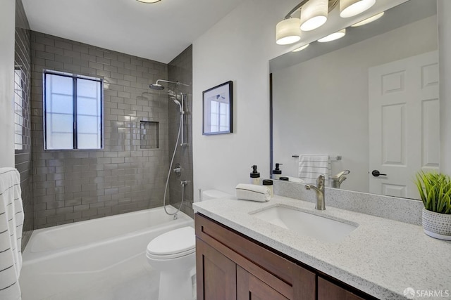 full bathroom featuring tiled shower / bath, vanity, and toilet