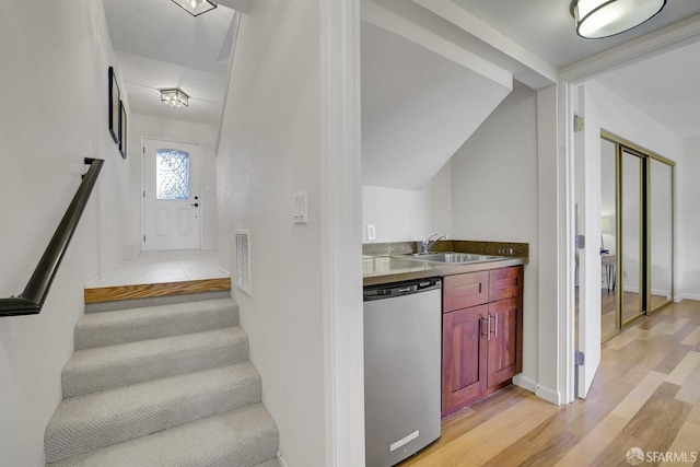 staircase with wood-type flooring, vaulted ceiling, and sink