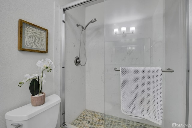 bathroom with a shower with door and toilet