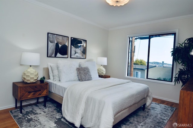 bedroom with crown molding, wood finished floors, and baseboards