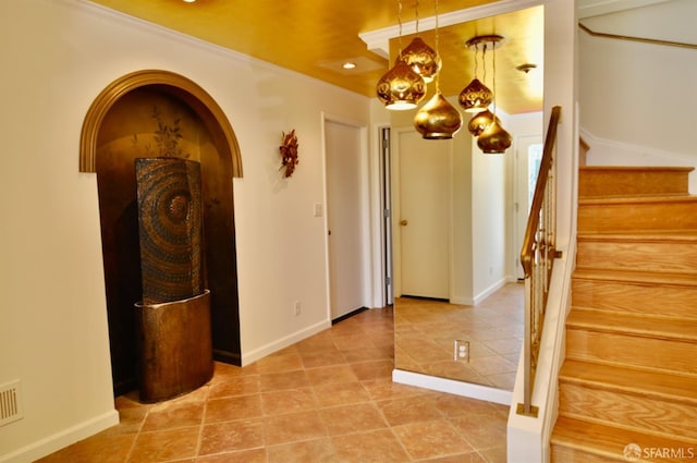 hallway featuring light tile patterned floors, baseboards, arched walkways, stairs, and crown molding