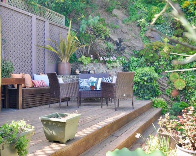 wooden terrace featuring an outdoor living space and fence