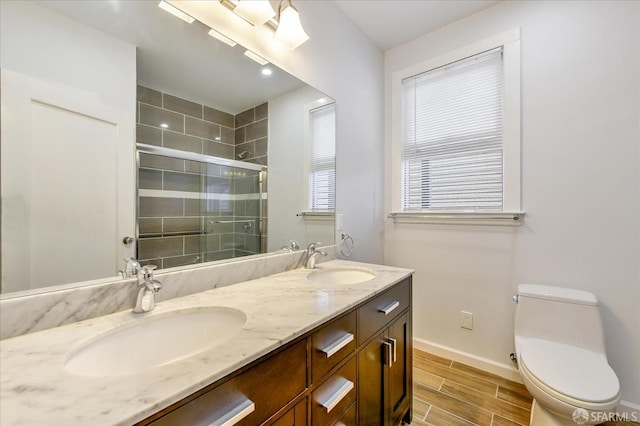 bathroom featuring a shower stall, toilet, a sink, and wood finish floors