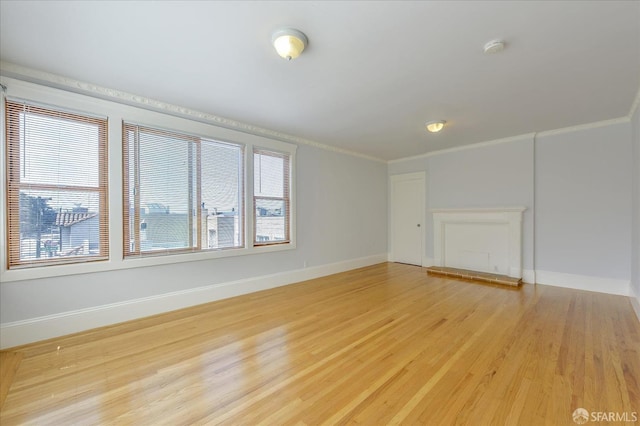 empty room featuring ornamental molding, light wood-style flooring, and baseboards