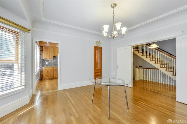 unfurnished dining area with a chandelier, light wood-style floors, baseboards, and stairs
