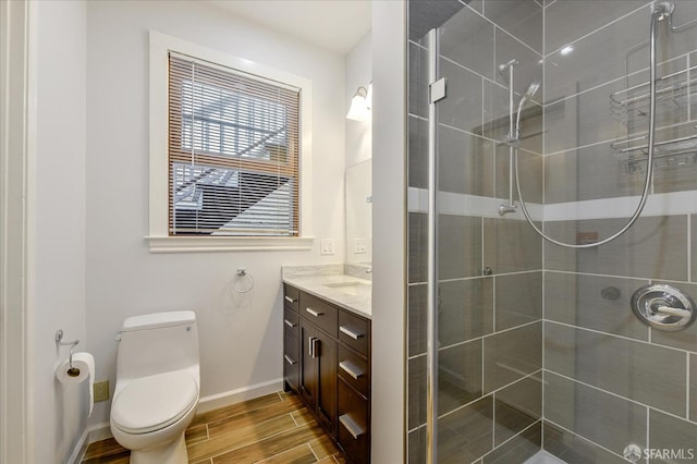 full bath with a shower stall, vanity, toilet, wood tiled floor, and baseboards