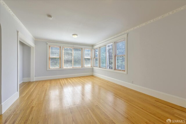 unfurnished room with ornamental molding, baseboards, and light wood finished floors