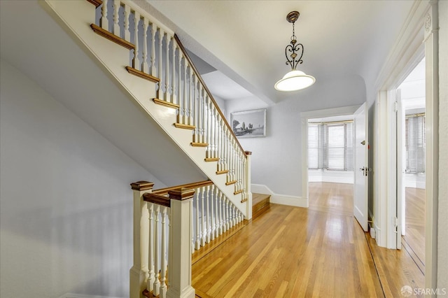entryway featuring wood finished floors, baseboards, and stairs