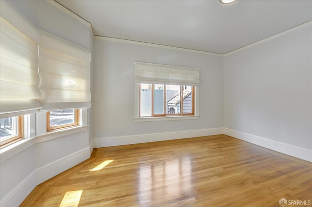 unfurnished room with light wood-type flooring, crown molding, and baseboards