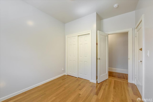 unfurnished bedroom featuring a closet, baseboards, and light wood finished floors