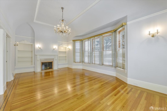 unfurnished living room with baseboards, an inviting chandelier, a fireplace with flush hearth, built in shelves, and wood finished floors