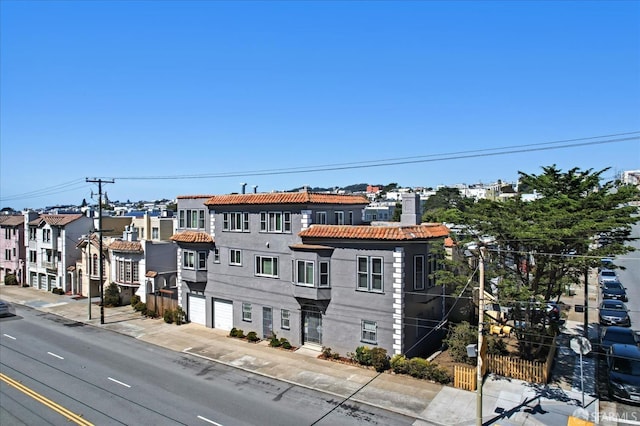 exterior space featuring a tiled roof, stucco siding, a residential view, and a chimney