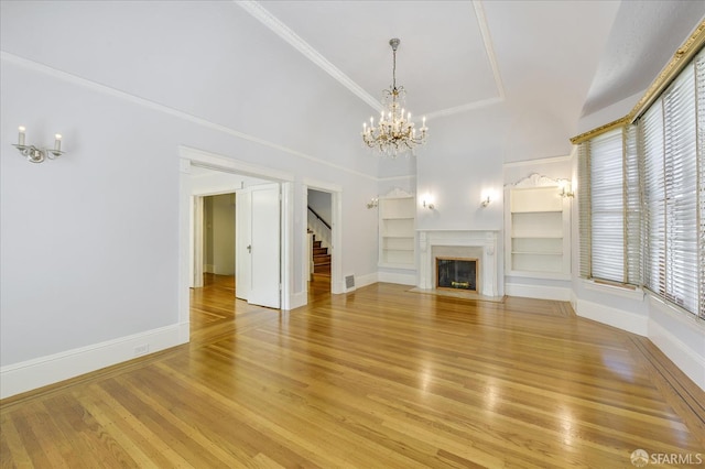 unfurnished living room with a notable chandelier, baseboards, built in features, stairway, and light wood-style floors