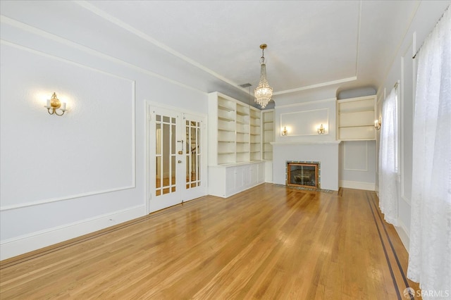 unfurnished living room featuring a fireplace with flush hearth, french doors, and wood finished floors