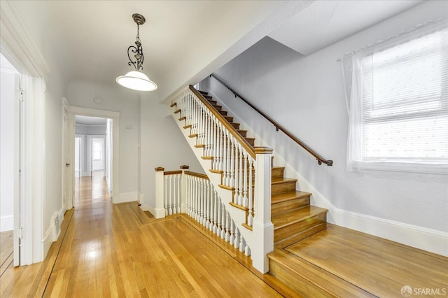 stairs featuring wood finished floors, baseboards, and visible vents