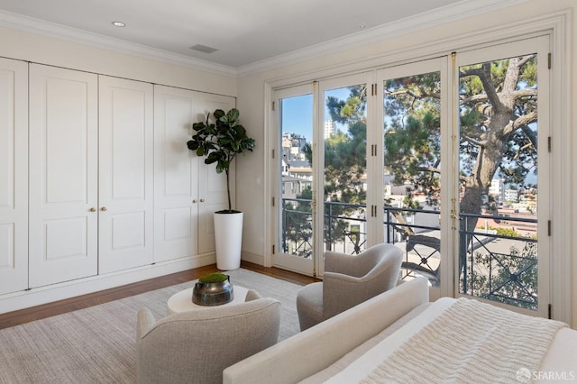 bedroom featuring multiple windows, hardwood / wood-style flooring, crown molding, and access to exterior