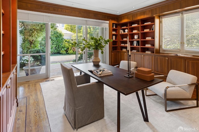 office space with ornamental molding, light hardwood / wood-style floors, and wooden walls