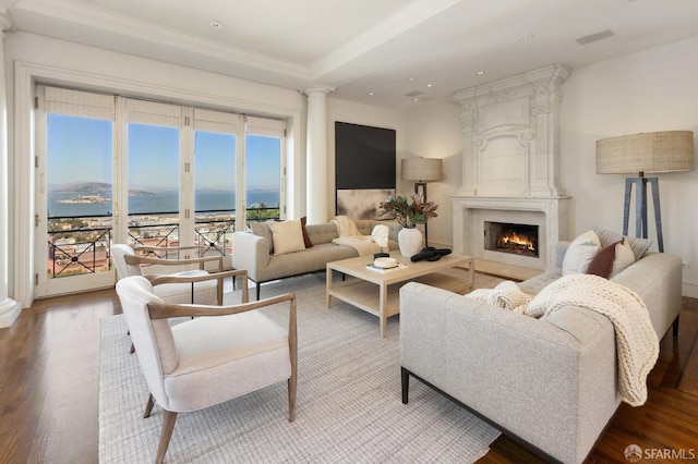 living room featuring a fireplace, ornamental molding, a water view, and hardwood / wood-style flooring