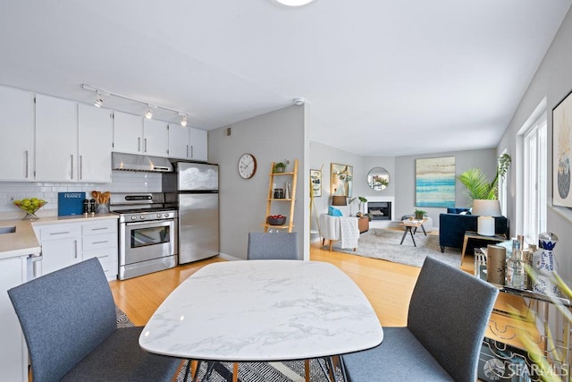 3421 25th St Unit 4, San Francisco, CA 94110 - kitchen with appliances with stainless steel finishes, under cabinet range hood, light countertops, backsplash, and white cabinetry