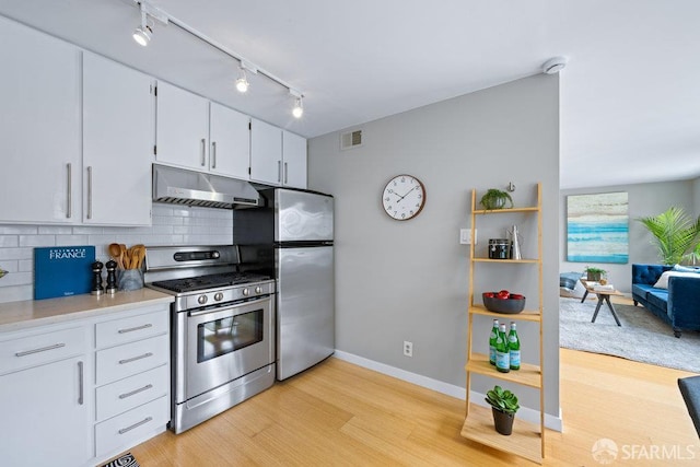 3421 25th St Unit 4, San Francisco, CA 94110 - kitchen with appliances with stainless steel finishes, under cabinet range hood, rail lighting, light wood-type flooring, and tasteful backsplash