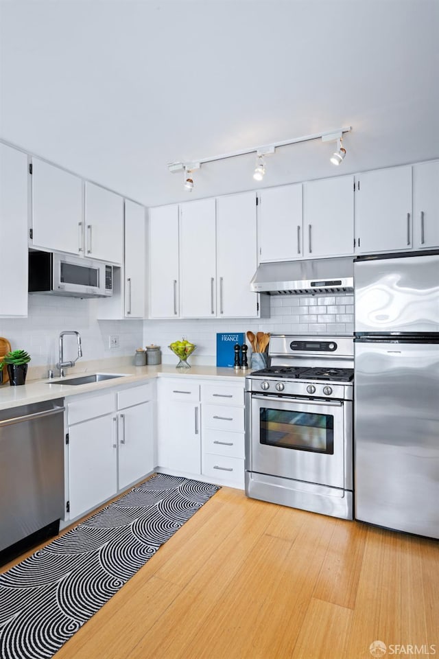 3421 25th St Unit 4, San Francisco, CA 94110 - kitchen featuring stainless steel appliances, a sink, under cabinet range hood, light countertops, and backsplash