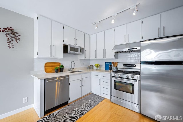 3421 25th St Unit 4, San Francisco, CA 94110 - kitchen with stainless steel appliances, under cabinet range hood, a sink, light wood-style flooring, and light countertops