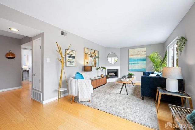 3421 25th St Unit 4, San Francisco, CA 94110 - living area featuring light wood-type flooring, a fireplace with raised hearth, and baseboards