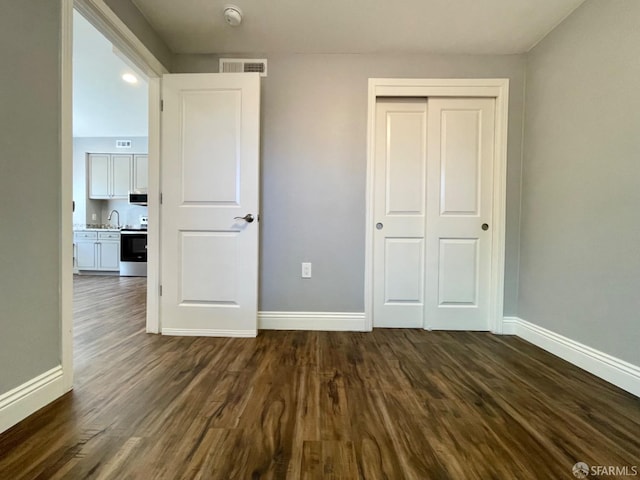 unfurnished bedroom with a closet, dark hardwood / wood-style floors, and sink