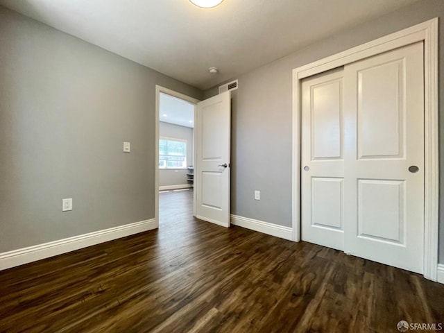 unfurnished bedroom featuring dark hardwood / wood-style floors and a closet