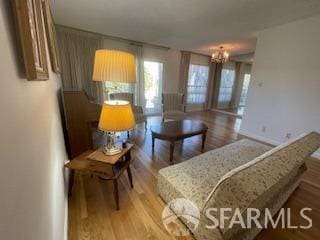 bedroom with baseboards, light wood finished floors, and an inviting chandelier