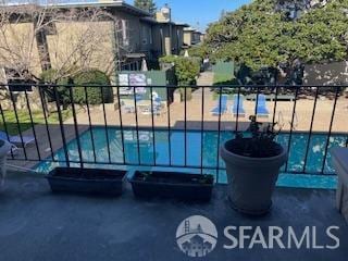 view of gate with fence and a community pool