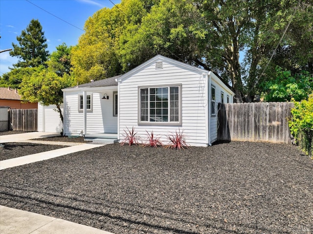 view of front facade featuring concrete driveway, fence, and a garage
