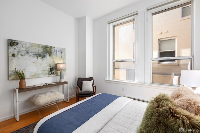 bedroom with hardwood / wood-style flooring and a baseboard heating unit