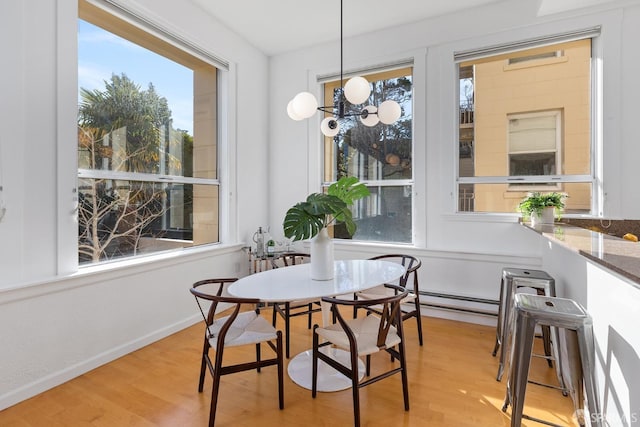 dining space with light hardwood / wood-style floors and a baseboard heating unit