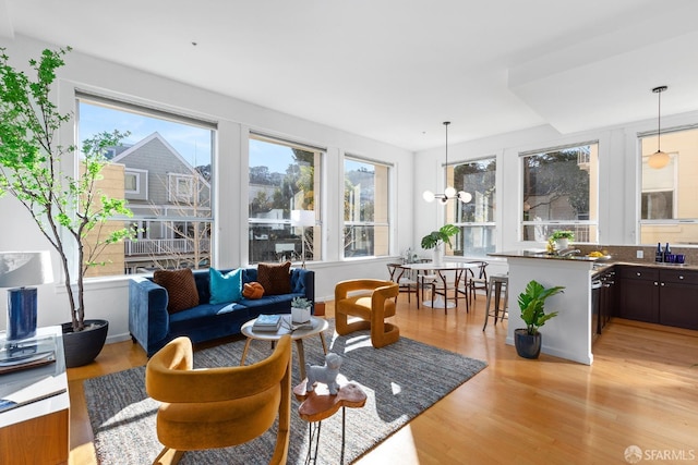 living room featuring a wealth of natural light, a chandelier, and light wood-type flooring