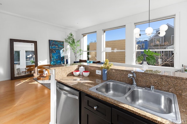 kitchen featuring sink, decorative light fixtures, light wood-type flooring, dishwasher, and dark stone counters