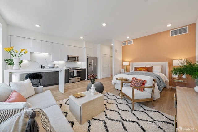 bedroom featuring light wood finished floors, recessed lighting, visible vents, and stainless steel fridge with ice dispenser