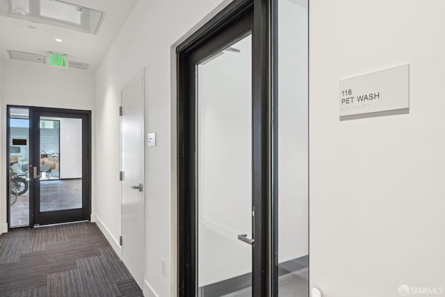 hallway featuring baseboards and dark carpet