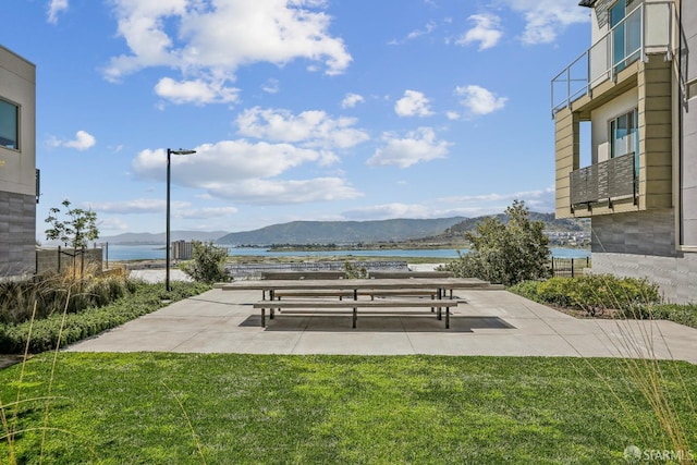 exterior space featuring a patio, a lawn, and a water and mountain view