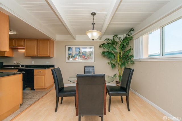 dining space with light hardwood / wood-style flooring, beamed ceiling, and sink