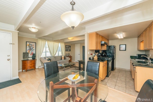 dining space featuring light wood-type flooring, beamed ceiling, and sink