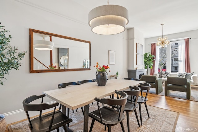 dining area featuring light wood-type flooring, a notable chandelier, and baseboards