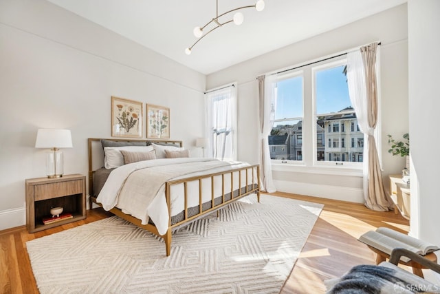 bedroom featuring light wood-type flooring, multiple windows, and baseboards