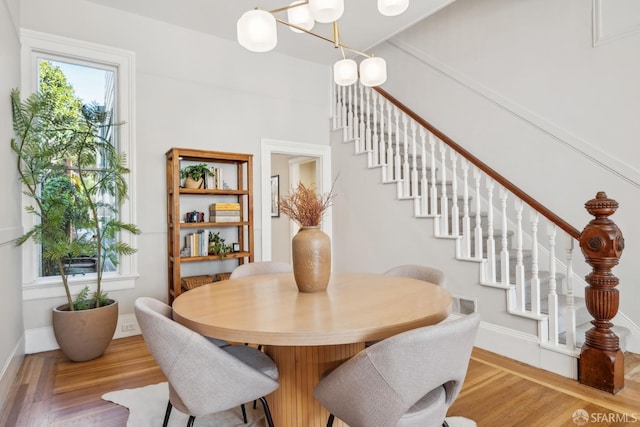 dining area featuring stairs, baseboards, a chandelier, and wood finished floors