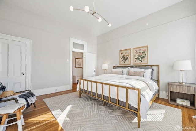 bedroom featuring a chandelier, baseboards, and wood finished floors