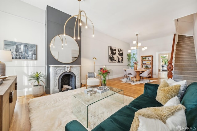 living room with baseboards, stairway, wood finished floors, an inviting chandelier, and a fireplace