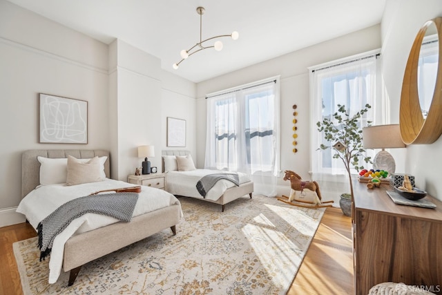 bedroom featuring an inviting chandelier and light wood-style flooring